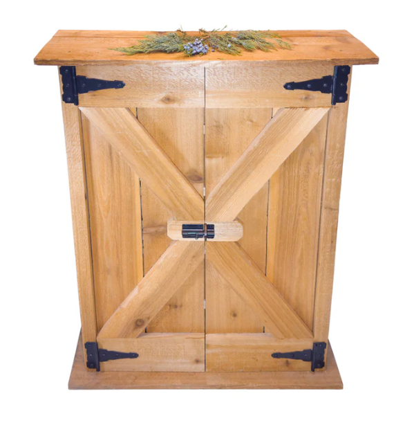 A rustic wooden cabinet with two doors featuring an X-brace design and black metal hardware, topped with a natural wood surface and a small greenery decoration.